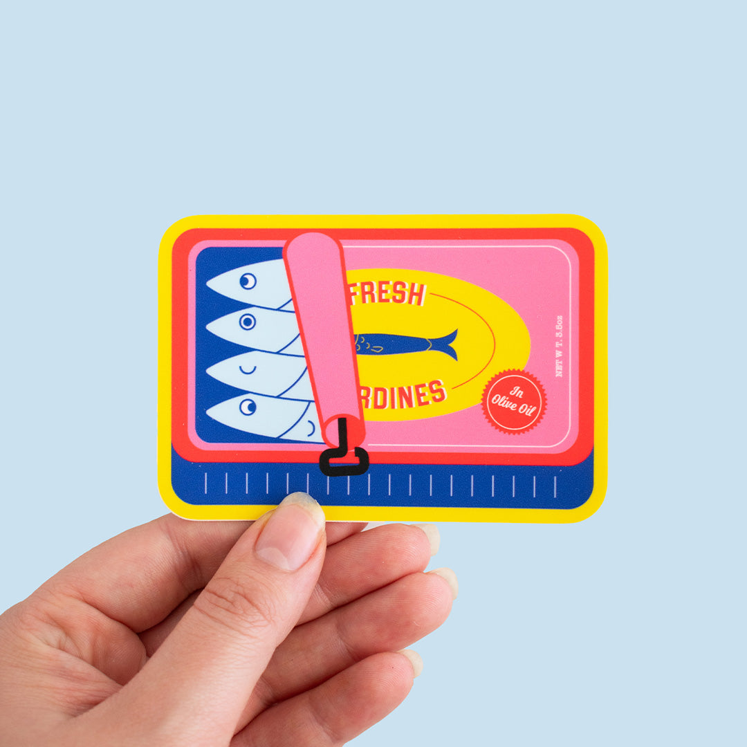 Person holding the Perfect Sardine Can Vinyl Sticker on a blue background.